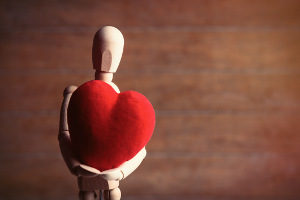 Photo of a wooden figure holding a red felt heart.