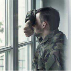Image of soldier looking out window suffering from PTSD