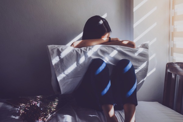 Woman in bed with her head in the pillow because she is struggling with depression