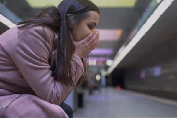An image of a woman struggling with a panic attack at a train station